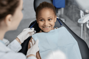 A happy young girl is receiving treatment at an edodontist's office.